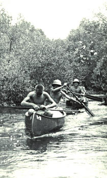 Na snímku není průzkumná výprava do povodí Amazonky, ale putovní tábor kanoistického oddílu plzeňské TJ Lokomotiva v létě 1953 na Lužnici. Do vodáckého světa kombinujícího romantiku s fyzickou dřinou a nutným kouskem řemeslné šikovnosti  vstoupili na podzim 1956 i chlapci ze skupinky ilegálních skautů, kterou po Kahounově odchodu vedl Petr Vyleta. | Spisovna ORJ Plzeň­‑město, materiály 50. odd. Černá Střela